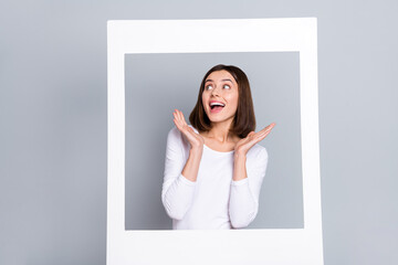 Poster - Photo of funny excited young lady dressed white clothes smiling standing white window looking empty space isolated grey color background