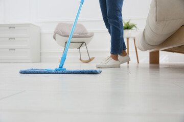 Poster - Woman cleaning parquet floor with mop at home, closeup