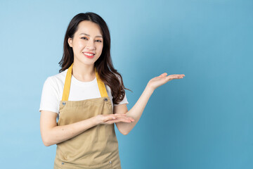 Wall Mural - Asian female waitress portrait, isolated on blue background