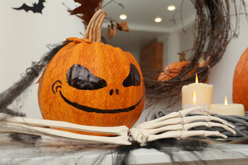 Wall Mural - Pumpkin with drawn spooky face and candles on table. Halloween decor