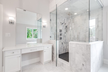 a bright luxury bathroom with a large shower and small, white vanity counter top. a stand alone bath