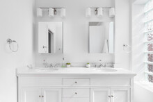 A Bright, White Bathroom With A Marble Countertop, Chrome Hardware And Faucets, And Block Window.