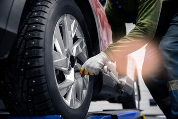 Wall Mural - Concept car service replacement of winter and summer tires. Mechanic unscrews wheel bolts from red auto