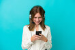 © luismolinero - Telemarketer English woman working with a headset isolated on blue background sending a message with the mobile