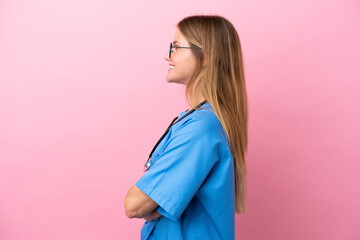 Young surgeon doctor woman isolated on pink background in lateral position