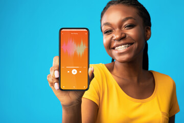 Music App. Cheerful Young Black Woman Demonstrating Audio Player Opened On Smartphone