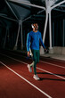 © ADDICTIVE STOCK - Athlete listening music and walking on the running track at night