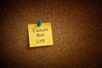 Wall Mural - A yellow sticky note with the phrase Simplify Your Life written on it pinned to a cork board