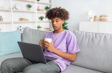 Wall Mural - Web-based education. Black teen boy drinking coffee, having video call with fellow students on laptop from home