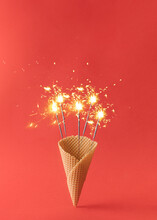Party Sparklers  In An Ice Cream Cone On A Red Background. Minimal New Year's Concept.
