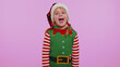 © Andrii Iemelianenko - Little bit crazy. Funny girl in Christmas Santa Claus helper Elf costume demonstrating tongue out, fooling around, making silly faces, madness on violet background. Happy New Year celebration holiday