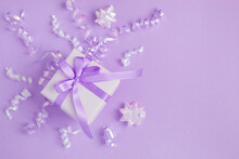 Gift Box With Tied Purple Bow And Confetti On The Puple Background. Top View.Copy Space.
