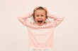 An angry little girl loses her temper holding her head, argues, complains, looks angry and dissatisfied, screams in rage, stands on a white background.
