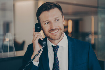 Satisfied male office worker calling his wife to notify her about promotion