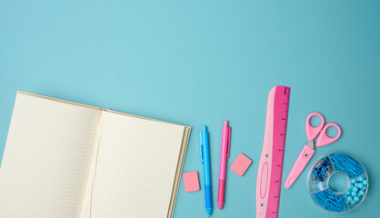 Wall Mural - open notebook with blank pink sheets, scissors and ruler on blue background, top view