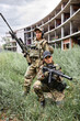© Roman - Two young women friends in camouflage holding guns weapon rifle before war fight , posing at camera, looking confidently. Caucasian ladies in military gear are ready to shoot, protect the world