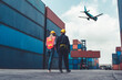 © InfiniteFlow - Industrial worker works with co-worker at overseas shipping container port . Logistics supply chain management and international goods export concept .