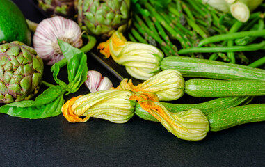 Wall Mural - Zucchini with flowers and variety of green vegetables on dark background, copy space