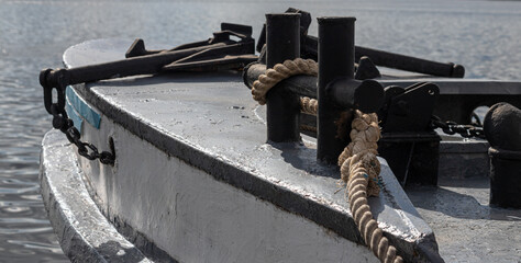 Worn old rusty mooring bollard with heavy ropes on the deck of a ship, closeup