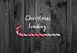Christmas concept with loading bar in candy cane form, holiday sweet peppermint stick showing progress on dark wooden boards background and inscription, xmas design with lollipop in minimalistic style