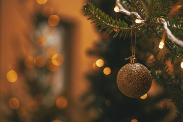 Christmas tree soft focus toy ball hanging on a branch and blurred background with warm color, bokeh and light