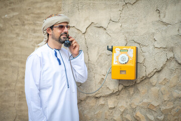 Wall Mural - Arab man making a call from a vintage phone in al seef district in Dubai