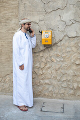 Wall Mural - Arab man making a call from a vintage phone in al seef district in Dubai