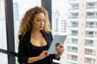 © Patcharanan - Young businesswoman executive using tablet on window with city building background.