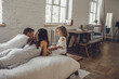 © Tatsiana - a little curly-haired girl is sitting next to the bed on which dad and mom are lying