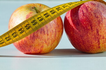 Set of two delicious and healthy apples with a measuring tape around