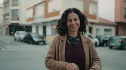 Wall Mural - Middle age hispanic woman smiling confident standing with arms crossed gesture at street