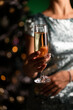 © Retan - Woman holding glass with champagne on a Christmas tree background