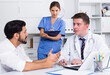 © JackF - Male doctor and female assistant working with patient in medical office writing prescription
