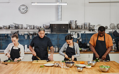 Wall Mural - Waist up portrait of diverse group of people cutting vegetables in cooking class