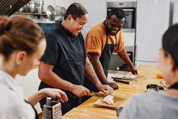 Wall Mural - Side view at tattooed female chef cooking with diverse team in kitchen, copy space