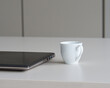 Kaffeetasse neben Laptop auf Schreibtisch - Coffee cup near laptop on work desk
