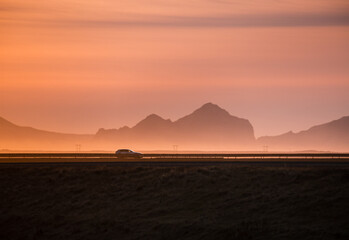 Wall Mural - Car driving at sunset in Icelandic Ring road with Westman Islands in the background