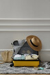 Open suitcase with summer clothes, accessories and shoes near white wall indoors, space for text