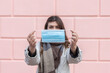© puhimec - Young woman with a protective mask on the background of the wall.