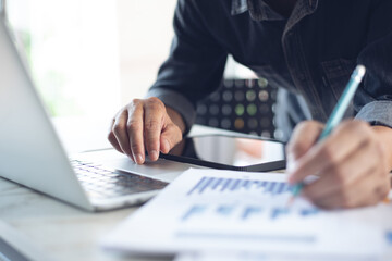 Wall Mural - Business man working at office with laptop computer and digital tablet and financial report graph data documents on his desk, close up