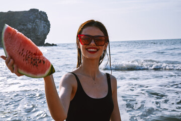 pretty woman in a black swimsuit with a watermelon in her hands summer Ocean