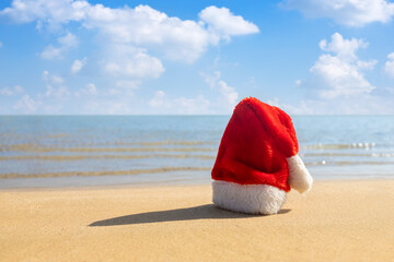 Wall Mural - Santa hat on sandy beach. Concept of celebrating new year