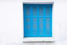 White Painted Wall With Closed Window, Frame With Typical Greek Blue Shutter, Lock Down, Space For Text, 