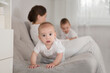 © ulza - portrait a smiling baby at home on the couch. mom plays and reads books with two  little kids.