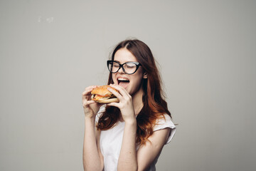 Wall Mural - woman with a hamburger in her hands a snack fast food close-up