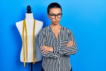 Poster - Beautiful hispanic woman with short hair standing by manikin skeptic and nervous, disapproving expression on face with crossed arms. negative person.