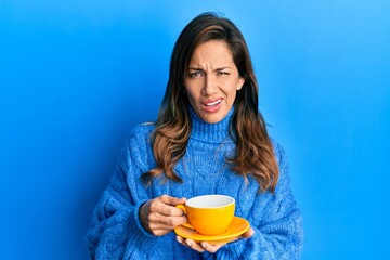 Poster - Young latin woman drinking a cup of coffee clueless and confused expression. doubt concept.