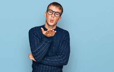 Poster - Young blond man wearing casual clothes and glasses looking at the camera blowing a kiss with hand on air being lovely and sexy. love expression.