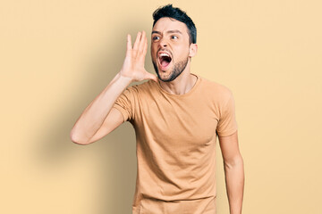 Poster - Hispanic man with beard wearing casual t shirt shouting and screaming loud to side with hand on mouth. communication concept.