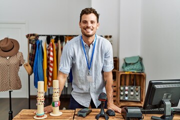 Sticker - Young hispanic shopkeeper man smiling happy standing by counter at clothing store.